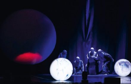 A photo from the production of Miguel Azguime's opera «A Laugh to Cry» featuring four of the singers and three globes.